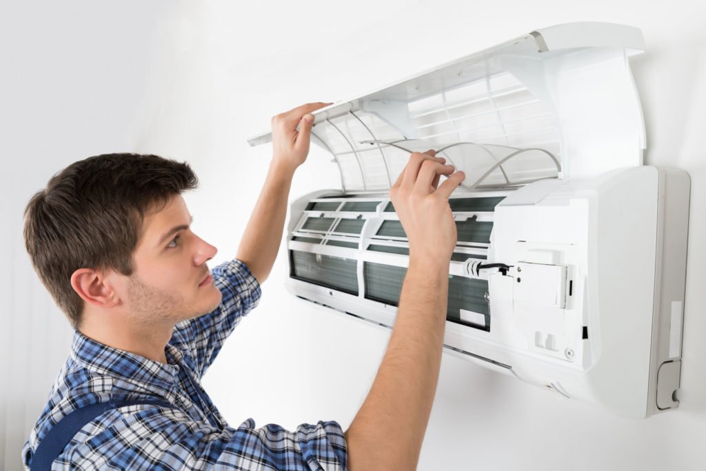 ouvrier technicien nettoyant le système de climatisation d'une maison, comparatif climatisation, réparation climatisation, prix climatisation, crédit d'impôt