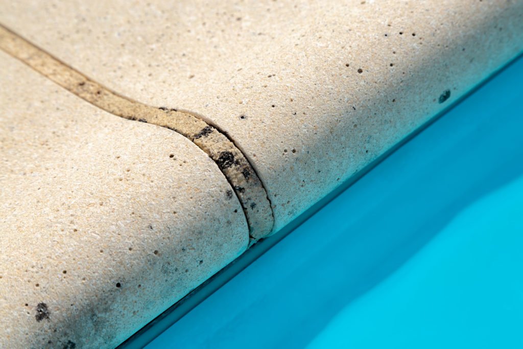 gros plan sur une margelle de piscine en pierre, piscine fibre de verre